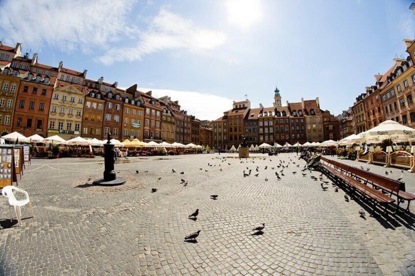 A cobblestone square with benches and a statue, surrounded by historic buildings and outdoor cafes. 3