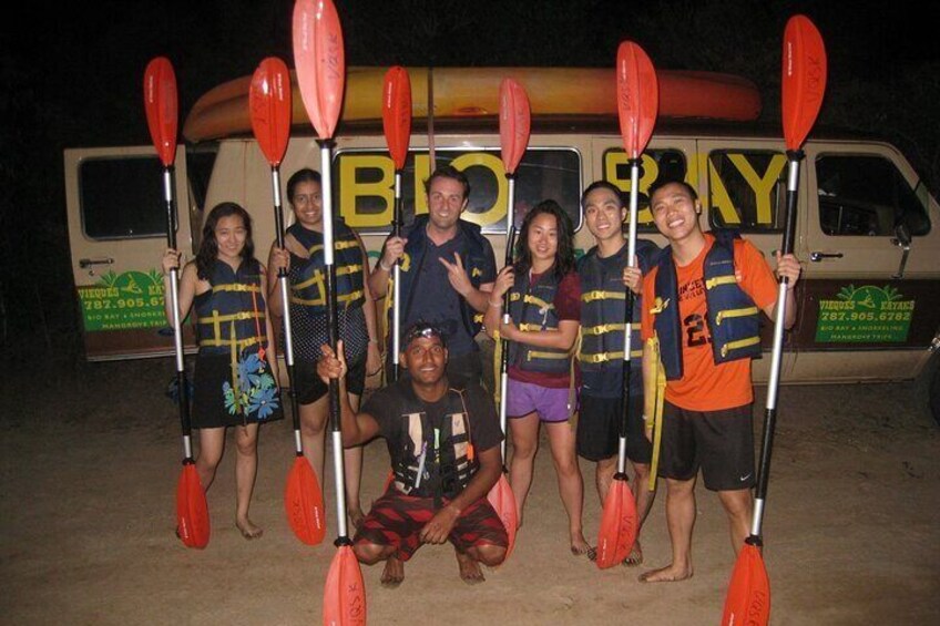 A group of people holding paddles in front of a van with 'BIKE' written on it. 1