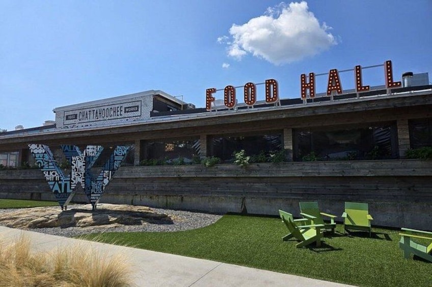 A building with a sign that reads 'FOOD HALL' and a large outdoor sculpture. 5