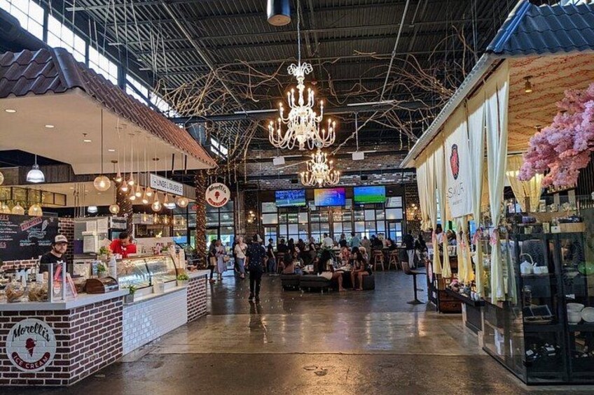 An indoor market with brick stalls, hanging lights, and a chandelier. 2