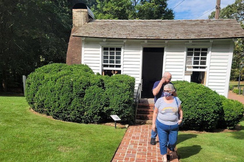 A white house with a brick chimney, a brick pathway, and a well-maintained hedge. 3
