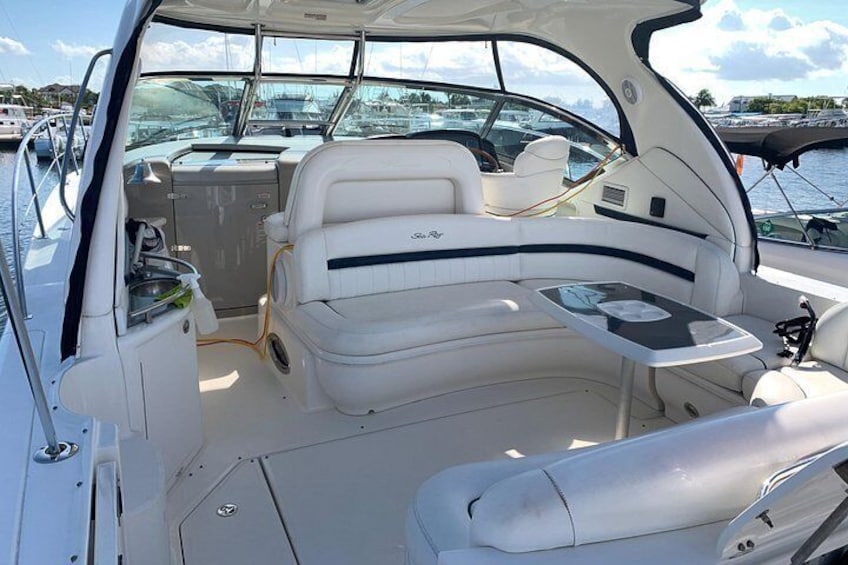 Interior de un barco con asientos, una mesa y un timón. 3