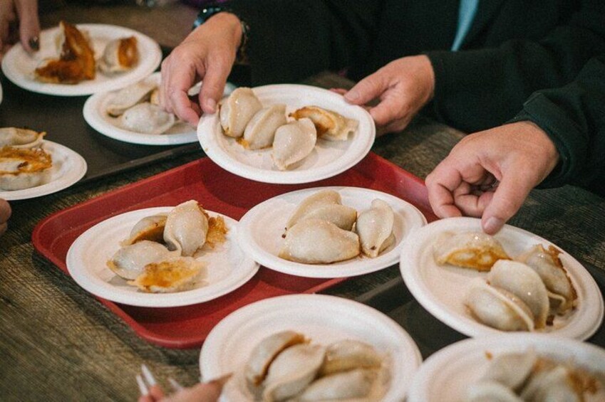 Personer som håller i tallrikar med dumplings. 3