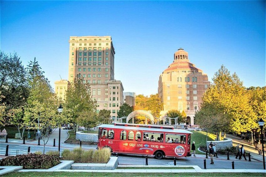 Un autobus rouge avec l’inscription « City Sightseeing », un grand bâtiment surmonté d’un dôme et des arbres dans un parc. 4