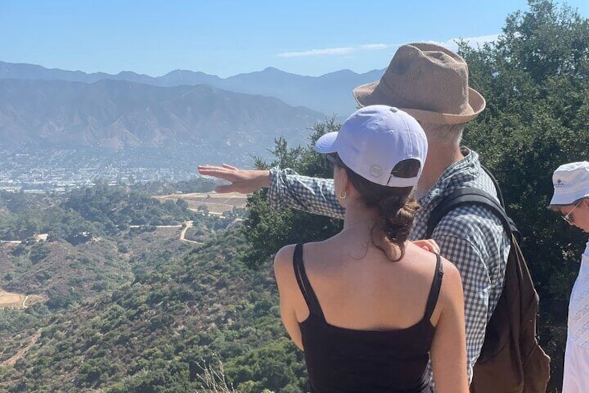 A couple standing on a hill overlooking a valley with mountains in the distance. 1