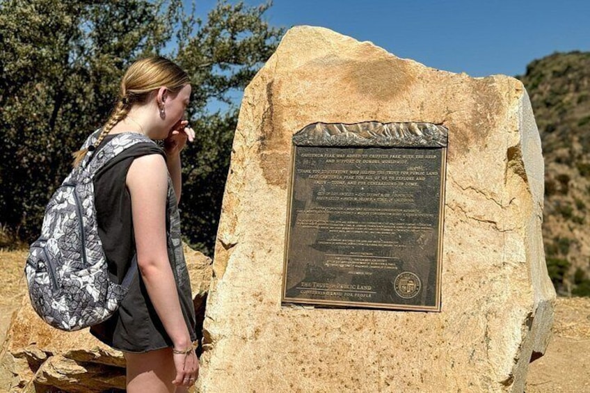 A person standing next to a large stone monument with an engraved plaque. 4
