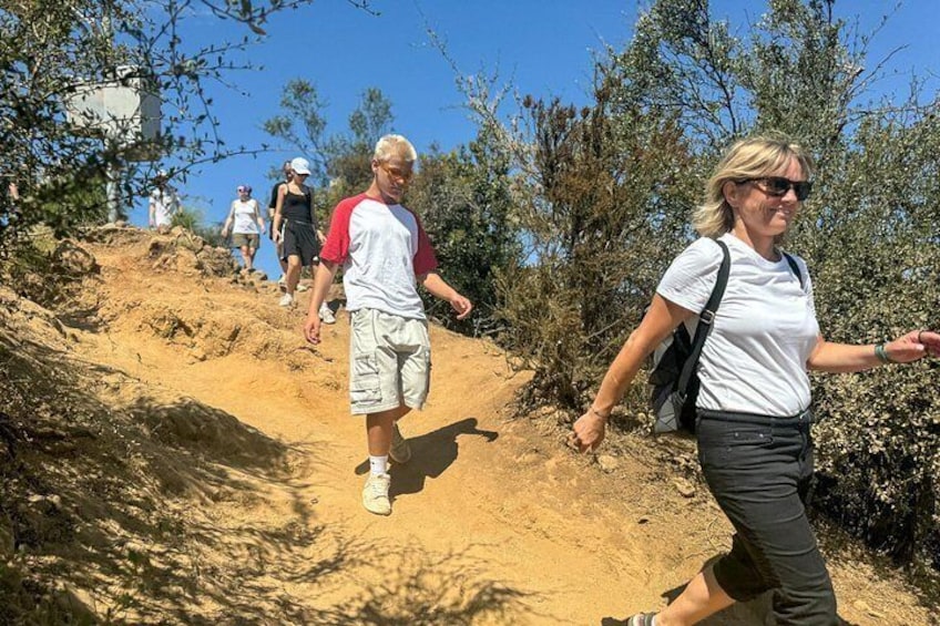 People hiking on a dirt trail surrounded by trees and shrubs. 5