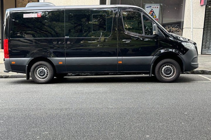 Een zwarte bestelwagen staat op een straat. 2
