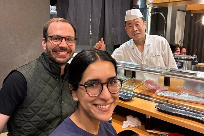 Un bar de sushi con un chef preparando comida. 3