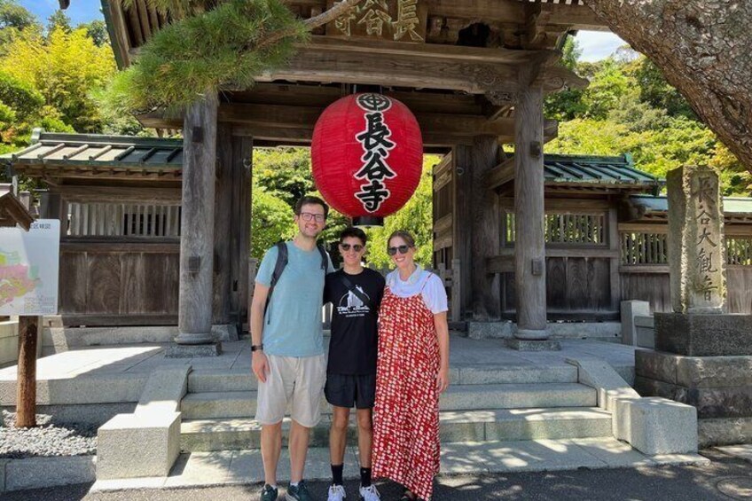 Three people standing under a traditional Japanese structure with a red lantern. 1