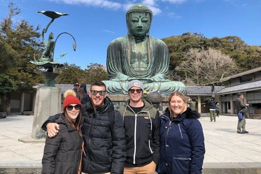 Una gran estatua de Buda en el patio de un templo, con visitantes. 1
