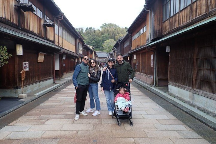 A group of people standing on a stone pathway between wooden buildings. 5