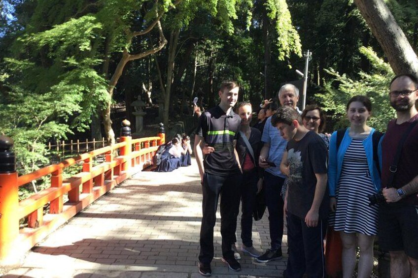 Un groupe de personnes se trouve sur un pont dont les garde-corps sont orange, et il est entouré d’arbres. 5
