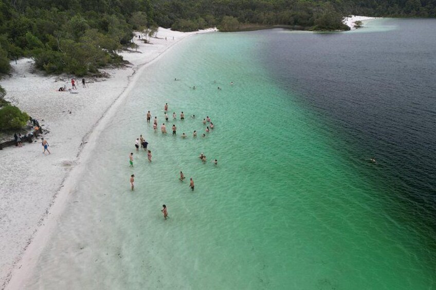 Ein Strand mit Menschen, die schwimmen und am Ufer entlanggehen. 3
