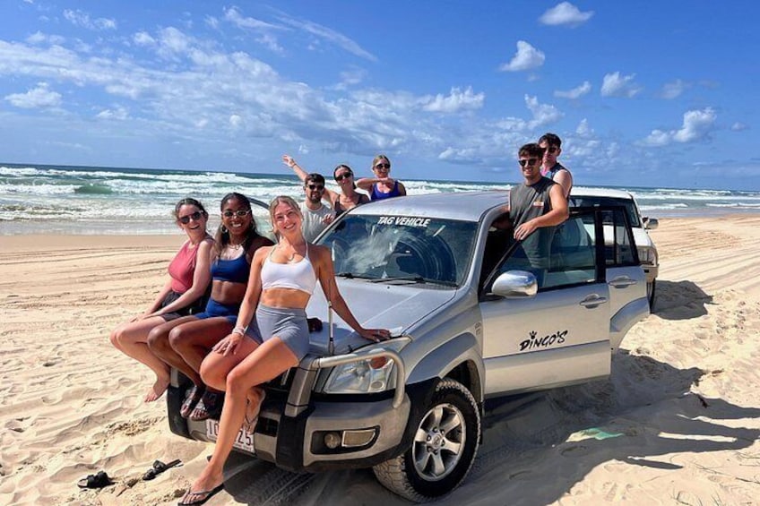 Un grupo de personas sentadas en un vehículo sobre una playa arenosa, con el océano al fondo. 5