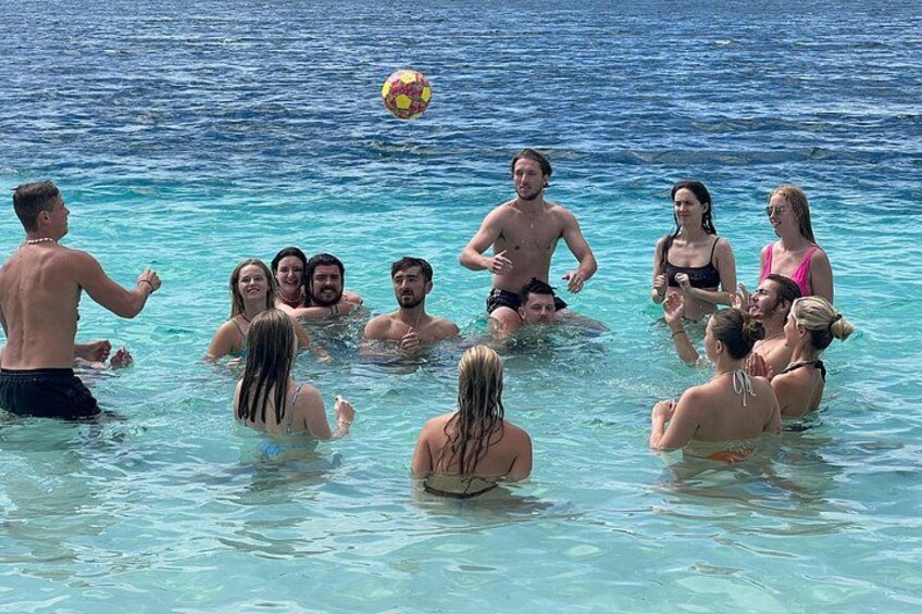 Eine Gruppe von Menschen spielt Volleyball in klarem, blauem Wasser. 4