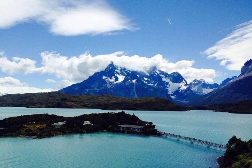 Un lago con un muelle, una pequeña isla y montañas nevadas al fondo. 3