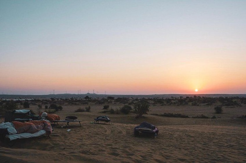 Woestijnlandschap in de zonsondergang met tenten en geparkeerde auto. 4