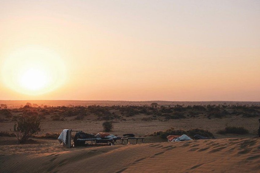 Woestijnlandschap bij zonsondergang met tenten en een voertuig. 3