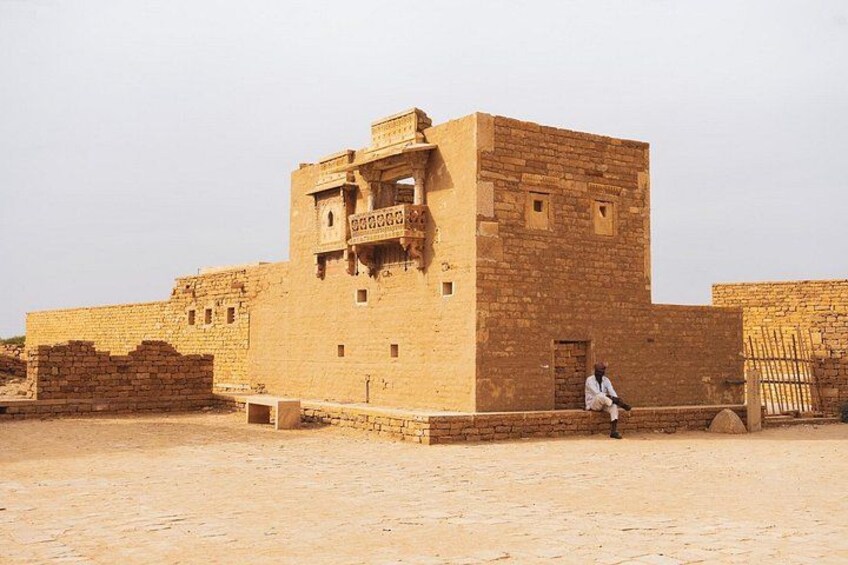 Un edificio storico con una persona seduta su una sporgenza. 4