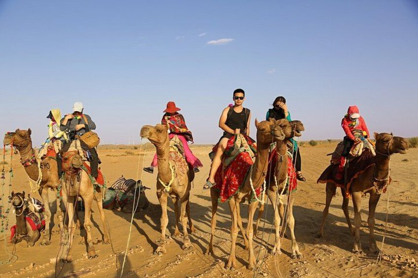 Un gruppo di persone cavalca dromedari nel deserto. 3