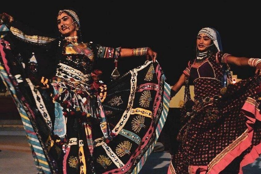 Two individuals in traditional attire, one holding a patterned fabric. 3