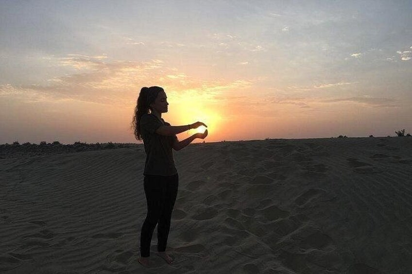 A person standing on a sandy beach at sunset. 1