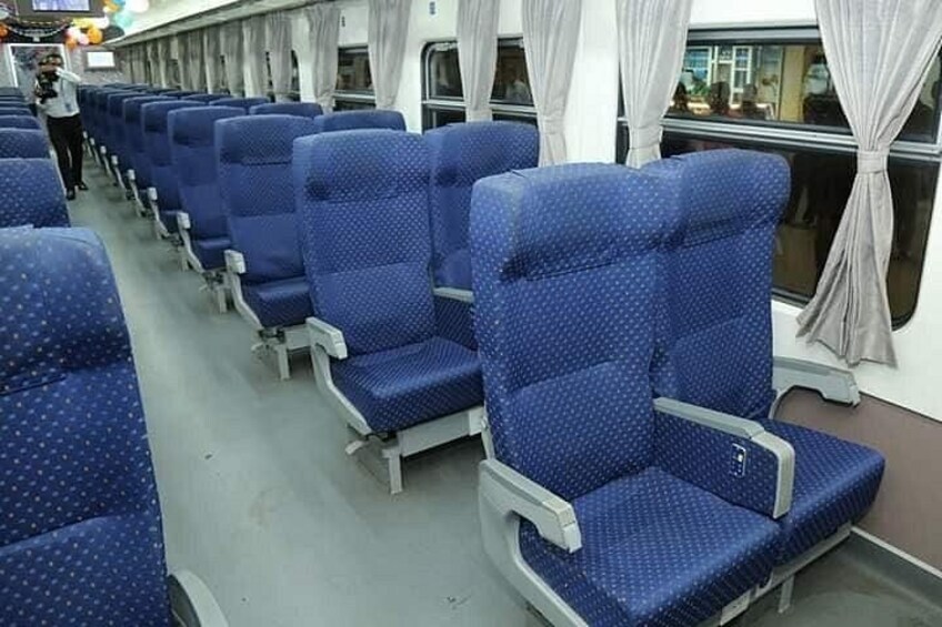 Rows of blue seats with grey armrests on a train. 5