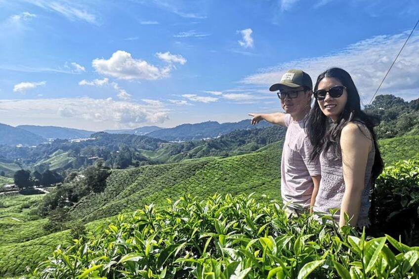 Two people standing on a hill with a view of a green landscape and distant hills. 1
