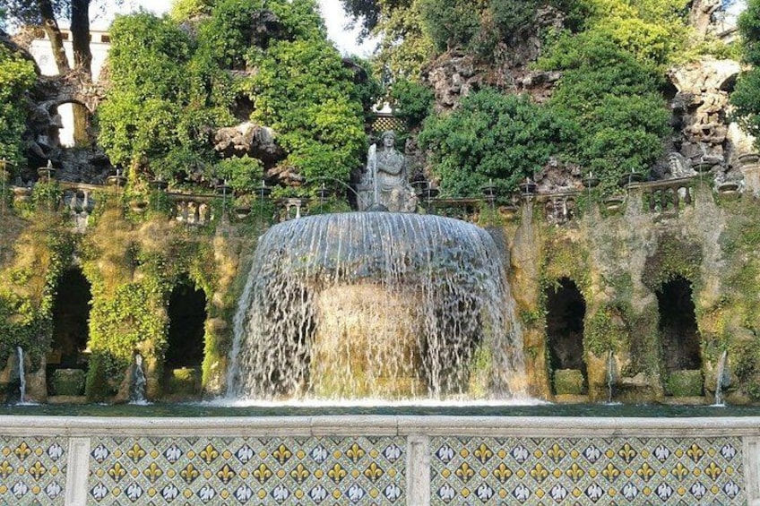 A fountain with water cascading down, surrounded by stone arches and lush greenery. 2