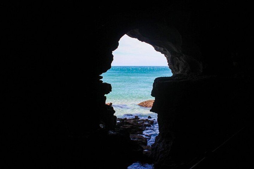 Una cueva que da a una playa con aguas cristalinas y rocas. 3