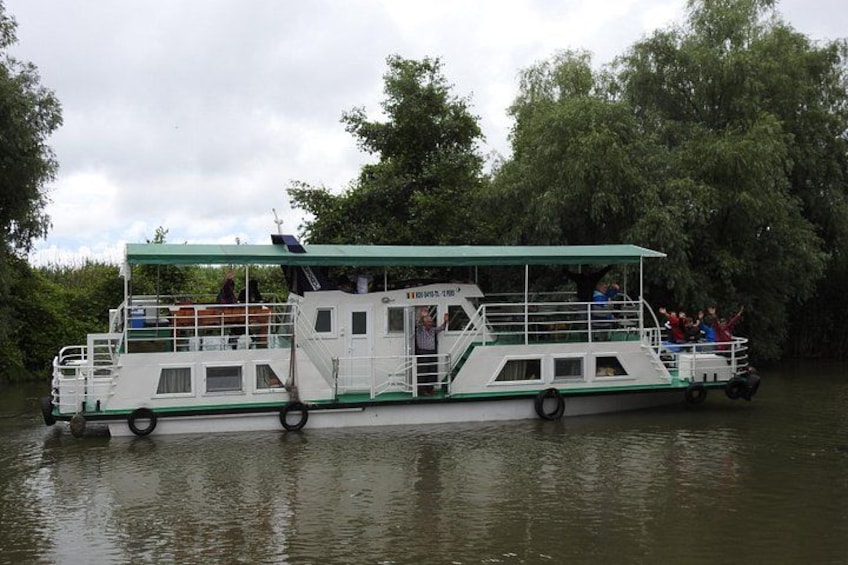 Een rivierschip met passagiers, omringd door bomen. 3