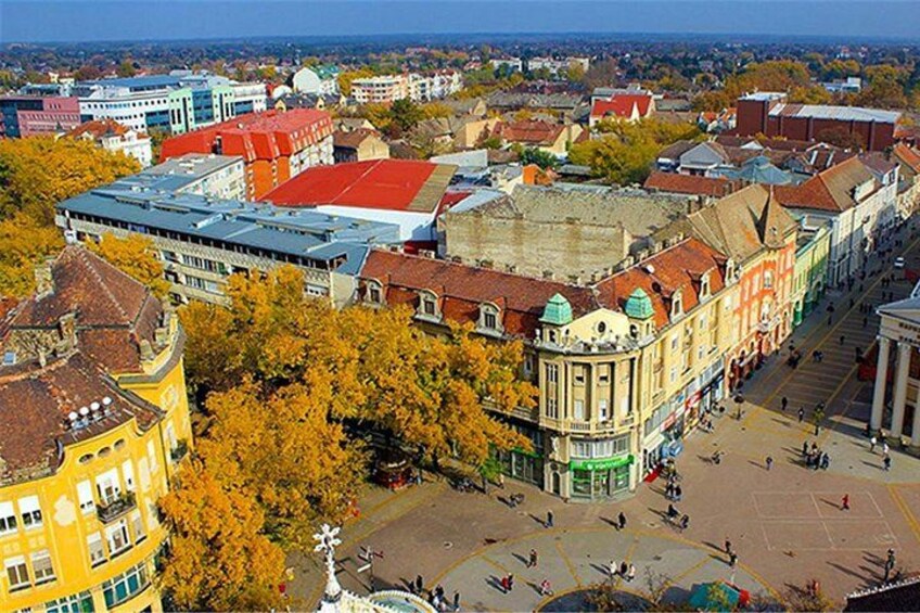 A cityscape with historic buildings, a central square, and autumn-colored trees. 4