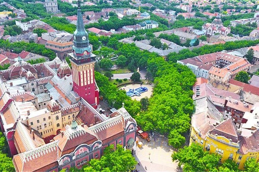 An aerial view of a historic city center with prominent buildings, a central square, and surrounding greenery. 5