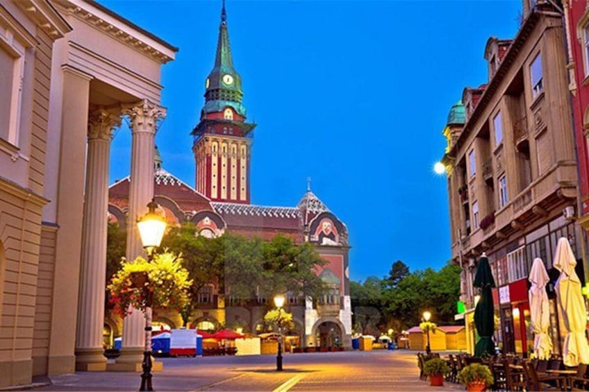 A historic building with a clock tower, street lamps, and outdoor seating. 3