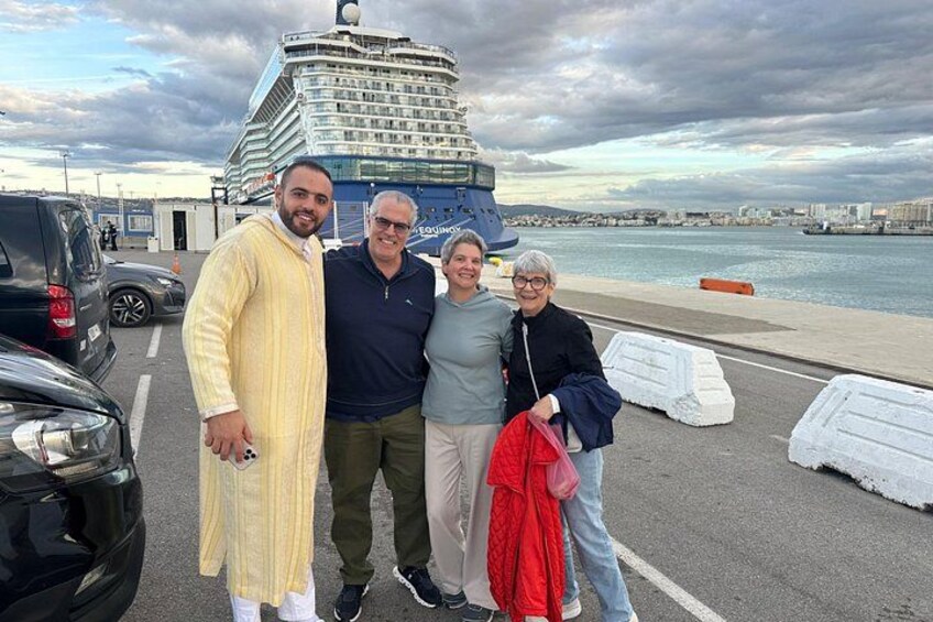 A group of people standing in a parking lot with a large cruise ship in the background. 2