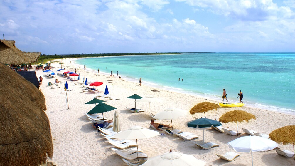 Umbrellas and beach goers on a sandy beach in Riviera Maya