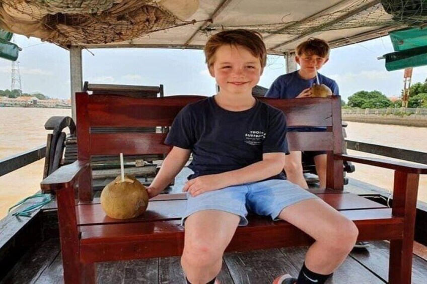 A person sitting on a wooden bench with a coconut drink on the table. 4