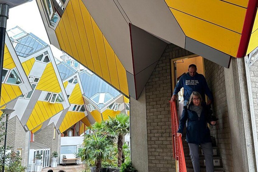 Un edificio con motivi geometrici gialli e bianchi, una persona che scende le scale e una palma. 5