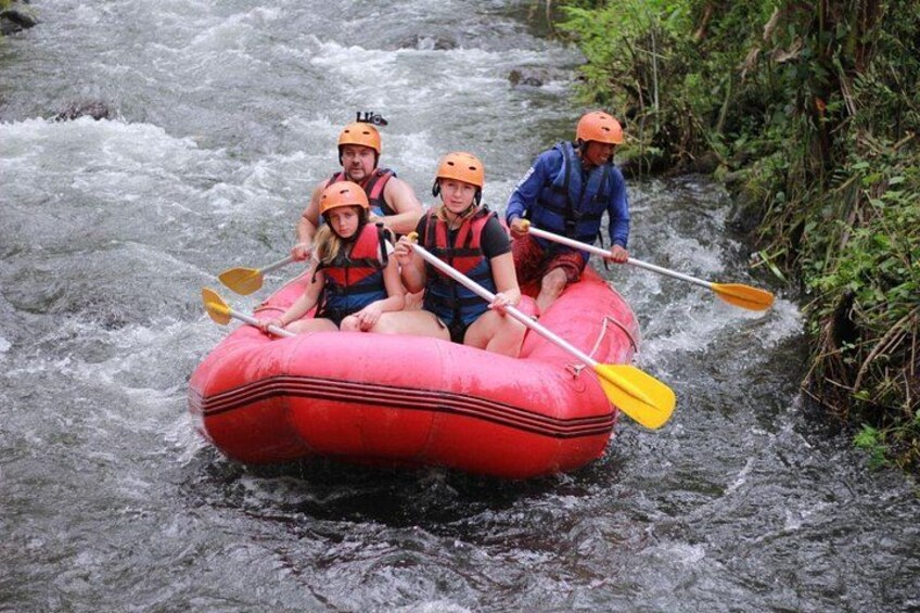 A group of people rafting down a river in a red raft. 2