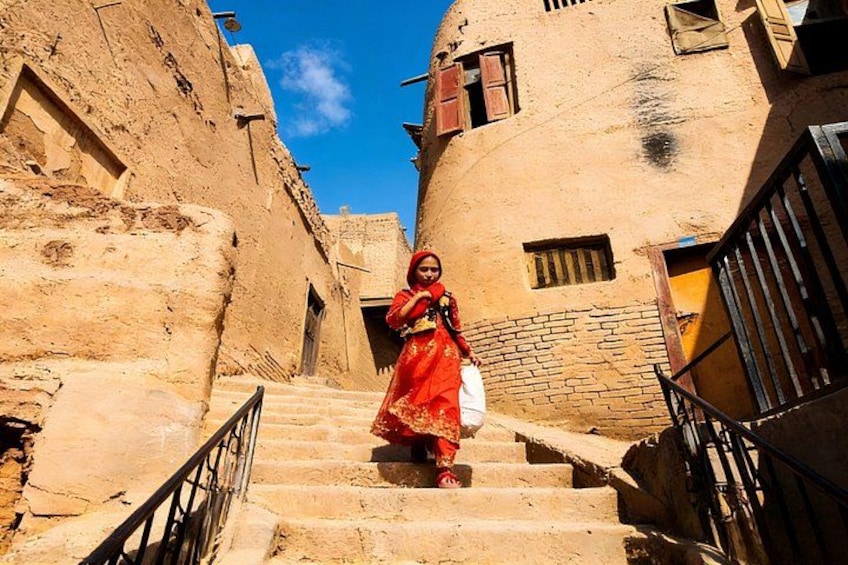 A person in a red dress descending a stone staircase in a narrow alleyway with traditional architecture. 2