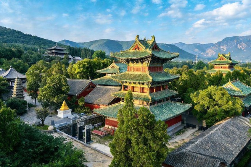 A traditional Chinese temple complex with pagoda-style architecture, surrounded by lush greenery and mountains in the background. 2