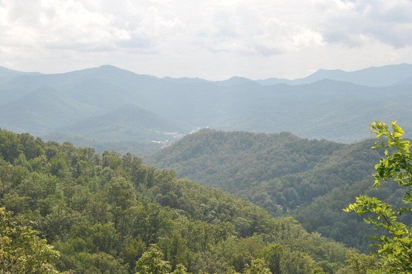A mountainous landscape with dense forest coverage and distant hills. 2