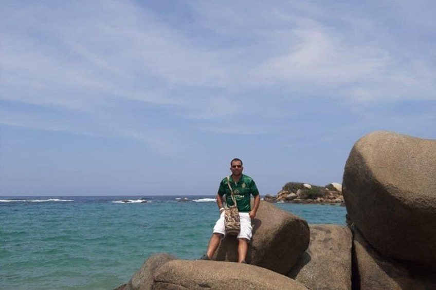 A person sitting on rocks by the ocean. 3