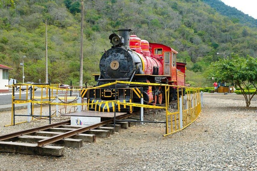 Eine Dampflokomotive mit der Nummer 7 auf Gleisen, umgeben von gelben Schutzbarrieren. 2