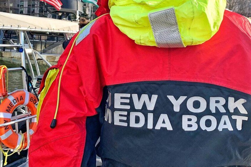 A person wearing a jacket with 'NEW YORK MEDIA BOAT' on the back. 4