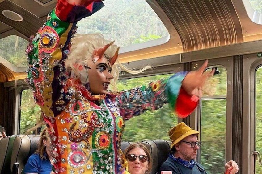 En person i farverigt kostume med maske sidder i et tog. 2