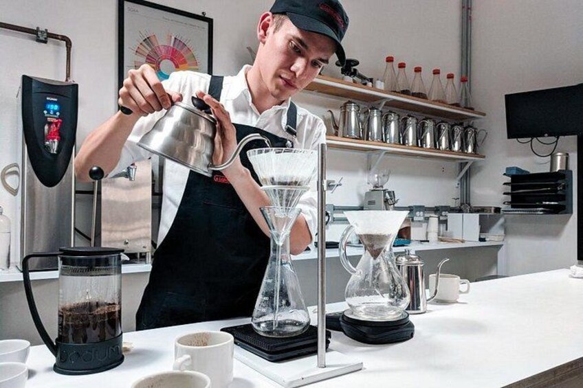 En person hælder kaffe i en glas kande. 3