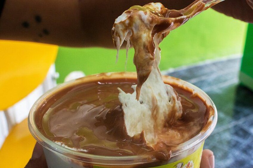 Une main tenant une cuillère, en train de puiser une crème dessert dans une tasse. 2
