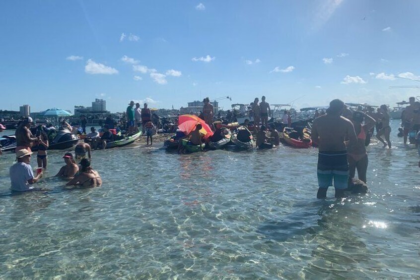 Personas en aguas poco profundas cerca de barcos, algunas de pie y otras sentadas. 4
